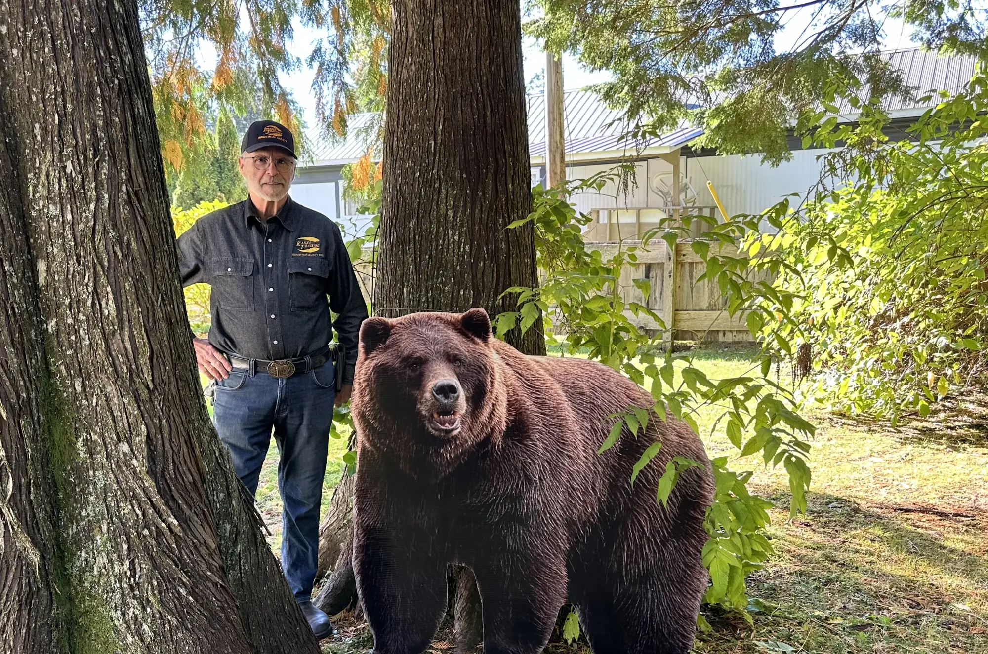 A photograph of Jack Cook, an experienced instructor at Karma Training, a premier safety training provider in Northwestern BC. He is standing near a large brown bear in a wooded area.